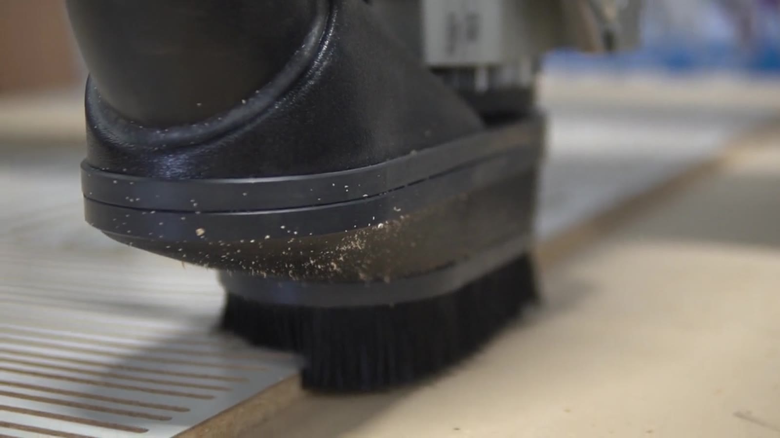The dust shoe of the CNC spindle close up, chips flying off a plywood sheet